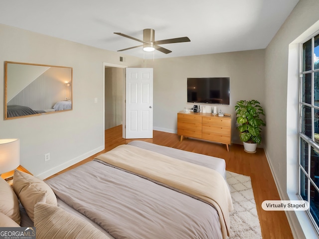 bedroom featuring ceiling fan, wood finished floors, visible vents, and baseboards