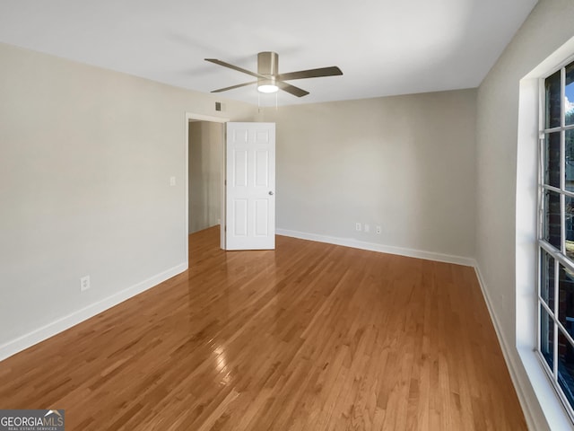 spare room featuring a ceiling fan, light wood-type flooring, visible vents, and baseboards