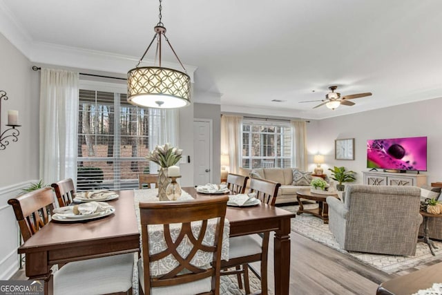 dining room with ornamental molding, a ceiling fan, and wood finished floors