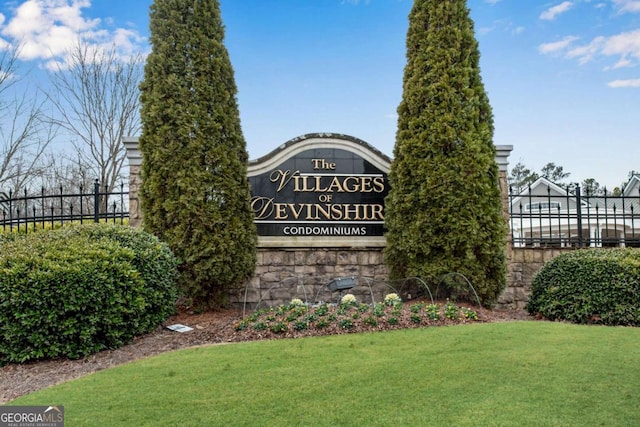 community / neighborhood sign with fence and a lawn