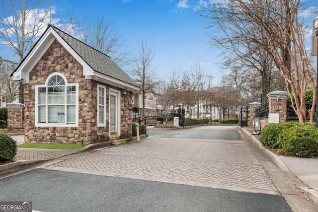 view of road with a gate, a gated entry, and curbs