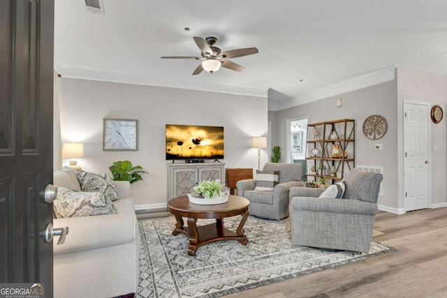 living area with crown molding, baseboards, and wood finished floors