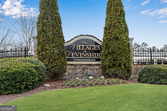 community sign featuring a lawn and fence