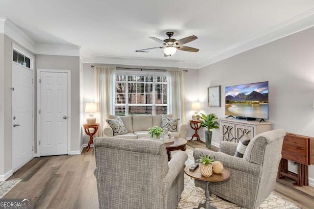 living area with ornamental molding, ceiling fan, baseboards, and wood finished floors