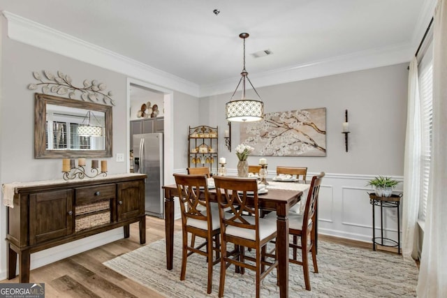 dining room featuring crown molding, visible vents, and light wood-style floors