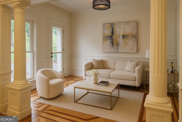 living area featuring a decorative wall, ornate columns, and ornamental molding