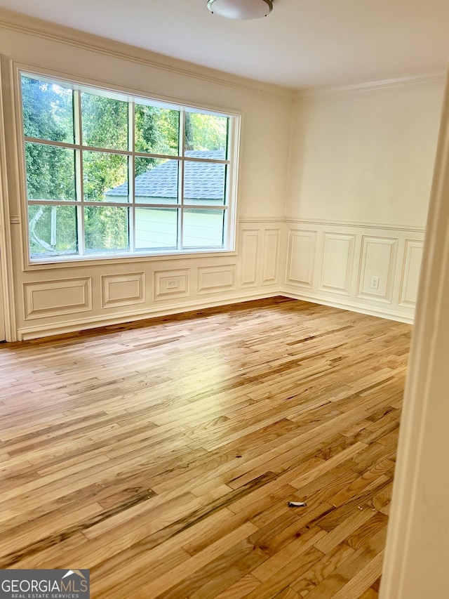 empty room with ornamental molding and light wood-type flooring