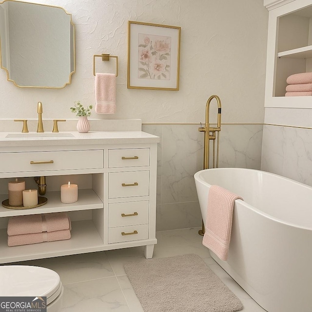 bathroom with marble look tiles, vanity, a freestanding bath, toilet, and tile walls