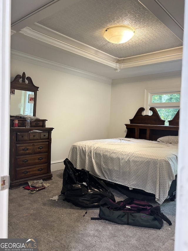 bedroom with ornamental molding, a tray ceiling, and carpet