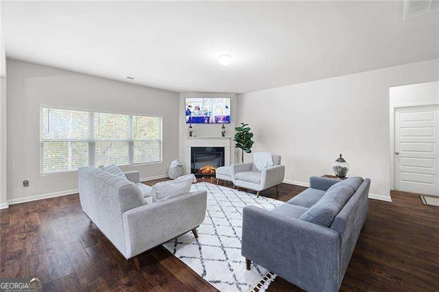 living room featuring hardwood / wood-style floors, a glass covered fireplace, and baseboards