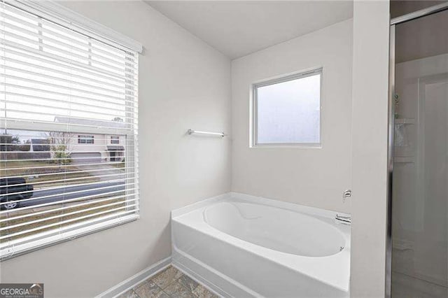 bathroom featuring a garden tub and baseboards