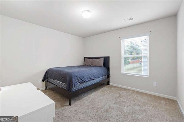 bedroom featuring visible vents, light carpet, and baseboards