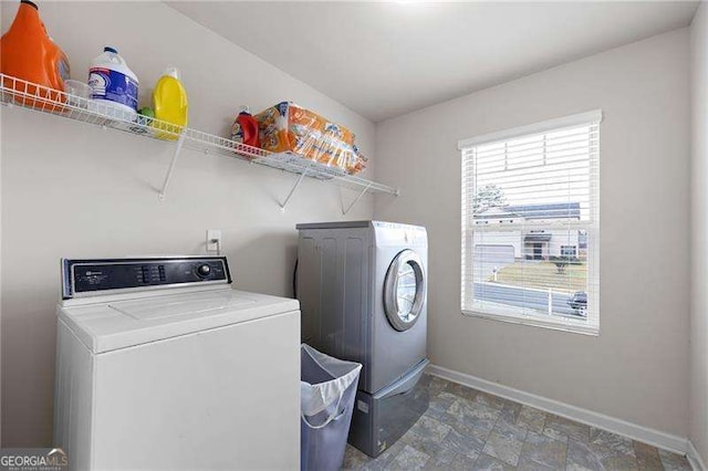 laundry room with laundry area, stone finish flooring, washer and clothes dryer, and baseboards