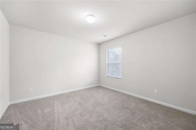 carpeted empty room featuring baseboards