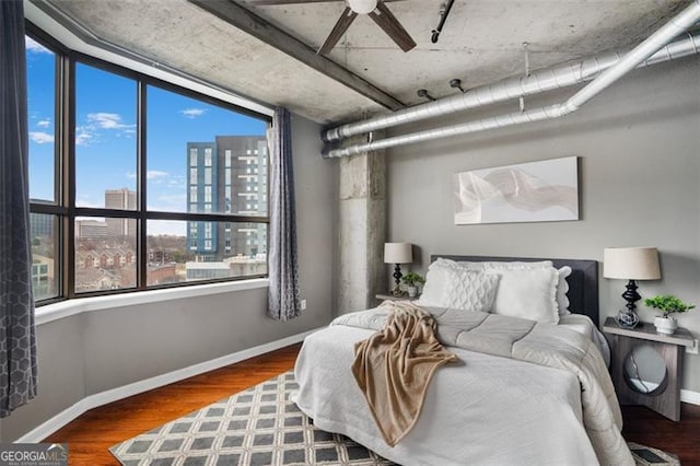 bedroom with ceiling fan, a view of city, baseboards, and wood finished floors