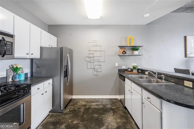 kitchen featuring stainless steel appliances, dark countertops, white cabinetry, a sink, and a peninsula