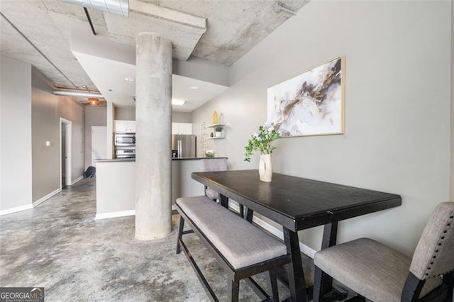 dining room with ornate columns, concrete floors, and baseboards