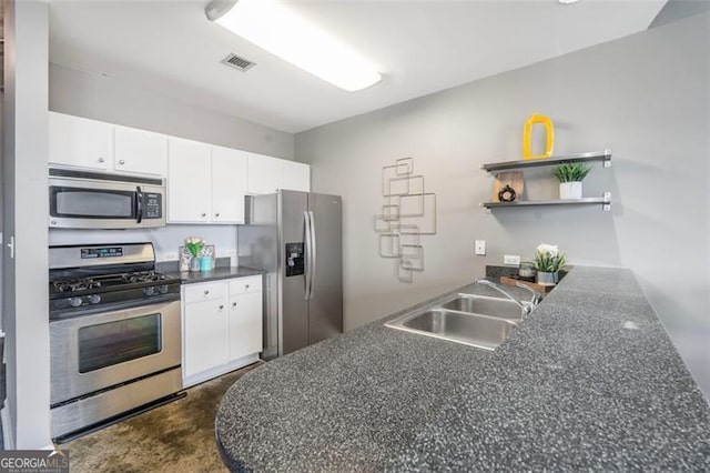 kitchen featuring open shelves, stainless steel appliances, dark countertops, white cabinetry, and a sink