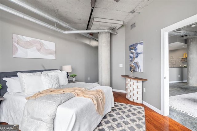 bedroom featuring baseboards, visible vents, and wood finished floors