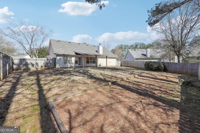 rear view of house with a gate, a fenced backyard, and a chimney