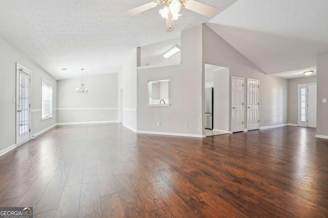 unfurnished living room with a textured ceiling, ceiling fan with notable chandelier, baseboards, vaulted ceiling, and dark wood-style floors