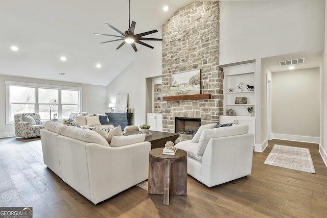 living area featuring dark wood-style floors, visible vents, and a stone fireplace