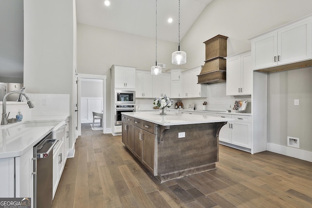 kitchen with stainless steel appliances, white cabinets, premium range hood, and a sink