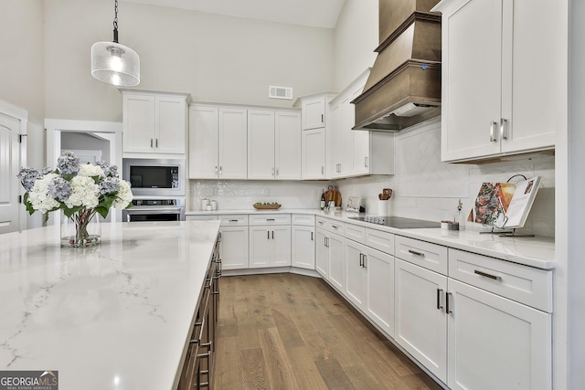 kitchen featuring stainless steel appliances, premium range hood, visible vents, and white cabinetry