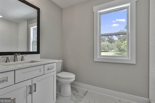 bathroom with marble finish floor, toilet, vanity, and baseboards