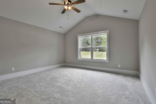 carpeted empty room featuring a ceiling fan, lofted ceiling, visible vents, and baseboards