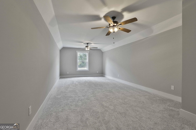 spare room featuring carpet flooring, vaulted ceiling, and baseboards