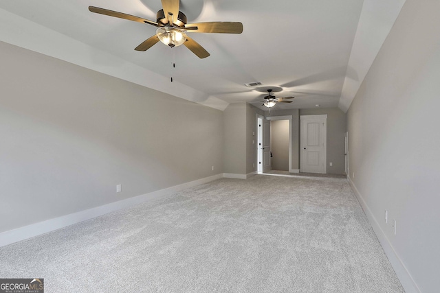 empty room featuring light colored carpet, visible vents, vaulted ceiling, and baseboards