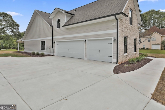 view of home's exterior featuring driveway, brick siding, roof with shingles, and an attached garage