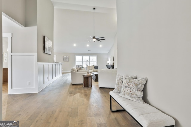 living area with a ceiling fan, high vaulted ceiling, and wood finished floors