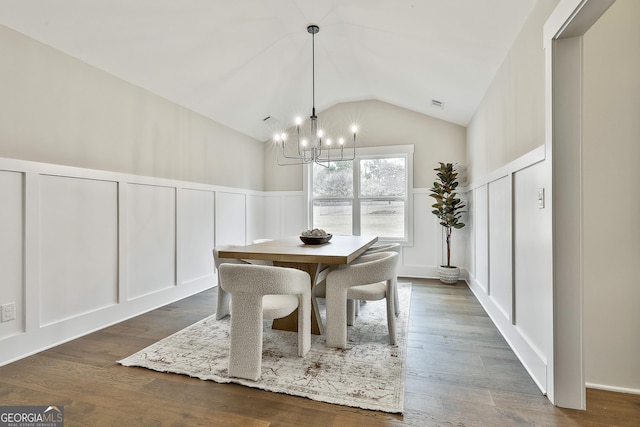 dining area with dark wood-style floors, visible vents, a decorative wall, an inviting chandelier, and vaulted ceiling