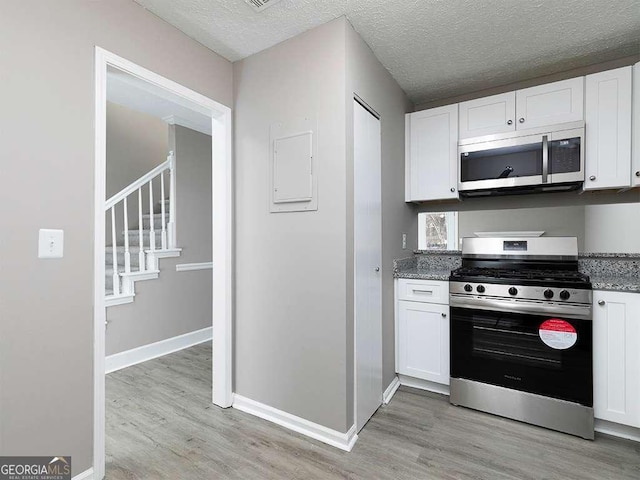 kitchen featuring stainless steel appliances, white cabinets, and light wood-style flooring