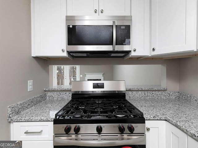 kitchen featuring light stone counters, appliances with stainless steel finishes, and white cabinetry