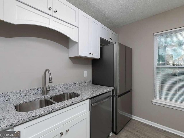 kitchen featuring dishwasher, wood finished floors, a textured ceiling, white cabinetry, and a sink