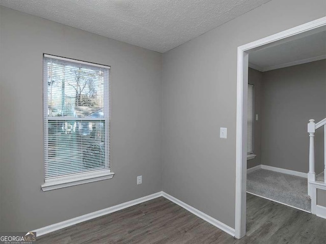 unfurnished room featuring dark wood-style flooring, a textured ceiling, and baseboards