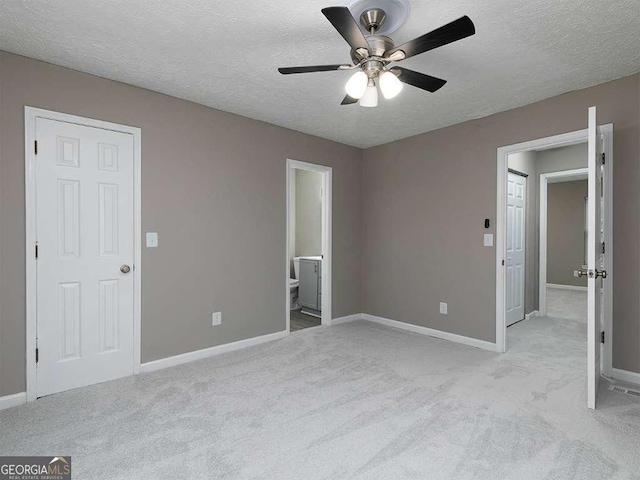 unfurnished bedroom featuring light colored carpet, a textured ceiling, and baseboards