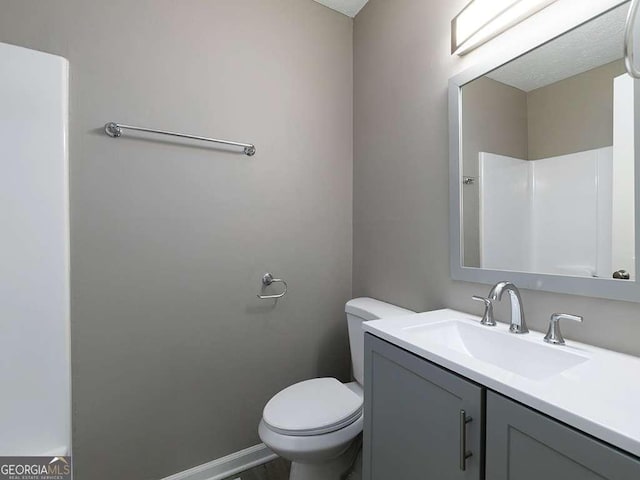 bathroom featuring vanity, toilet, and baseboards