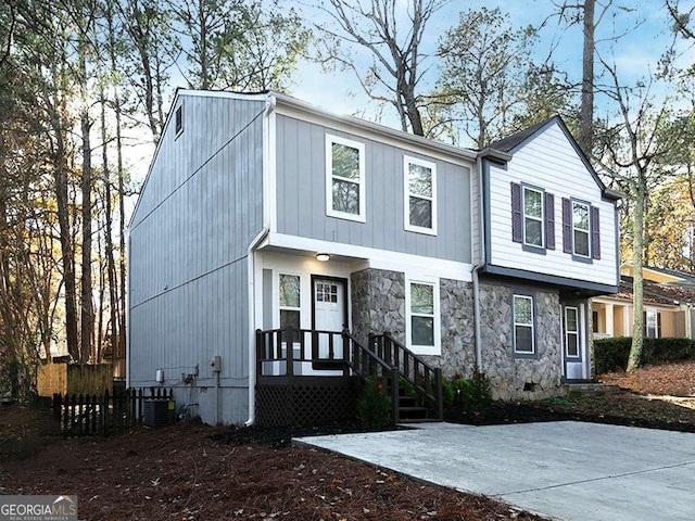 view of front of home featuring crawl space, stone siding, fence, and cooling unit