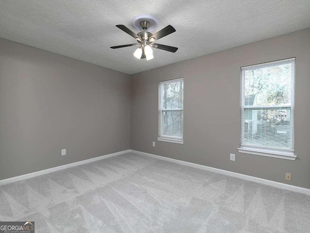 spare room featuring baseboards, ceiling fan, a textured ceiling, and light colored carpet