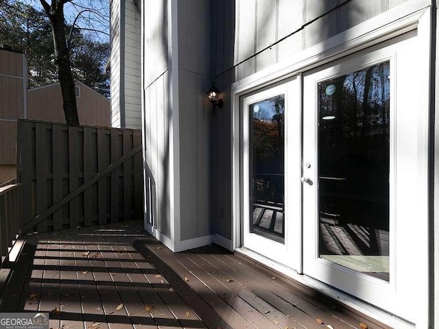 view of exterior entry featuring french doors, fence, and a deck