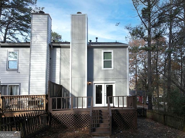 rear view of house featuring a chimney, fence, and a wooden deck