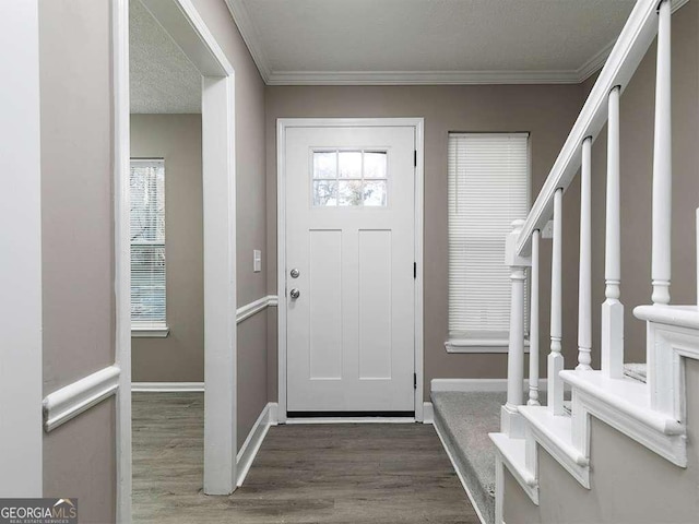 entryway featuring stairs, baseboards, wood finished floors, and ornamental molding