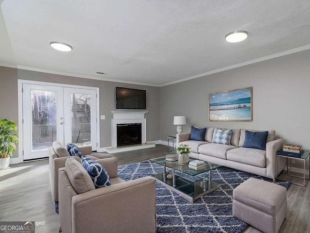 living area with crown molding, baseboards, a fireplace with raised hearth, and wood finished floors