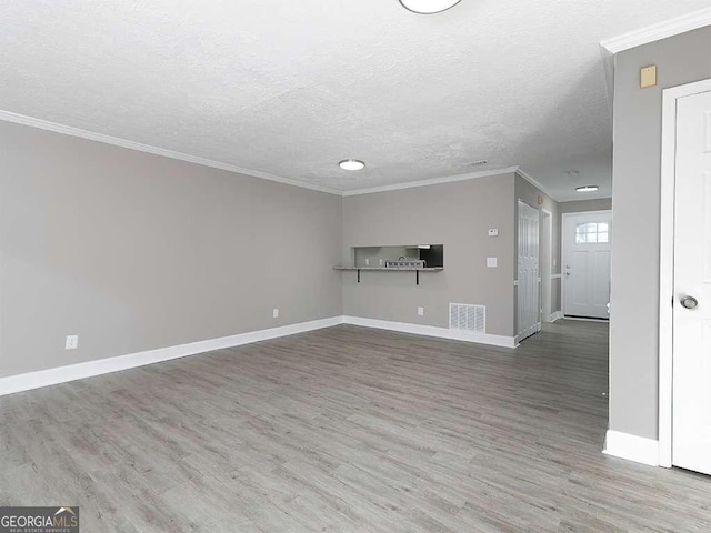 unfurnished living room with ornamental molding, baseboards, and wood finished floors