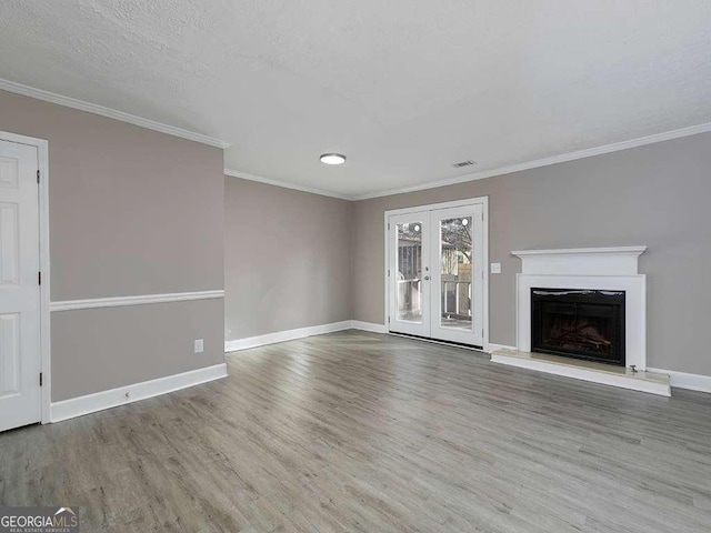 unfurnished living room featuring baseboards, a fireplace with raised hearth, wood finished floors, and ornamental molding