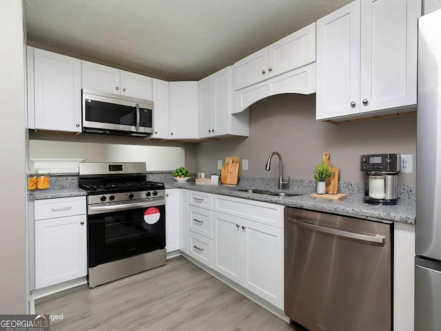 kitchen with appliances with stainless steel finishes, a sink, and white cabinetry